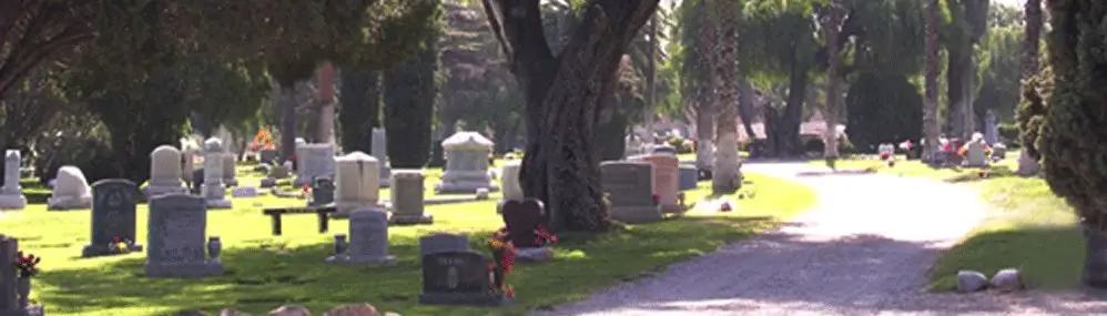 Scenic view of Corona Sunnyslope Cemetery with gravestones and peaceful pathways surrounded by trees.