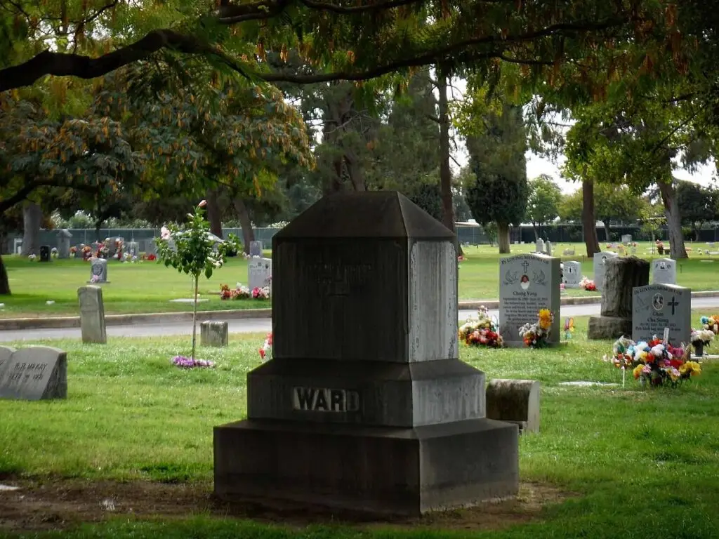 Historic headstone at Mountain View Cemetery, Fresno, surrounded by lush greenery and memorial flowers