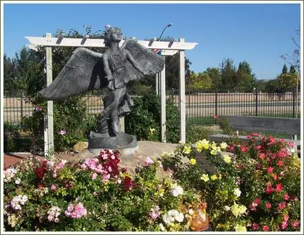 Angel statue at Santa Maria Cemetery District surrounded by flowers, symbolizing peace and remembrance.