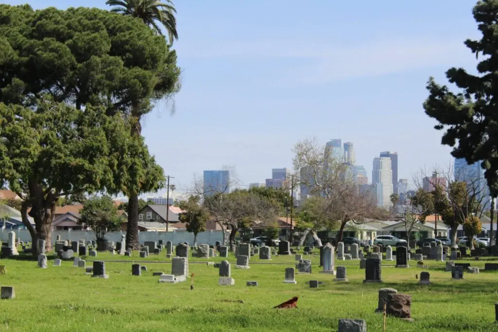 Scenic view of Angelus Rosedale Cemetery in Los Angeles with gravestones and the city skyline in the background.