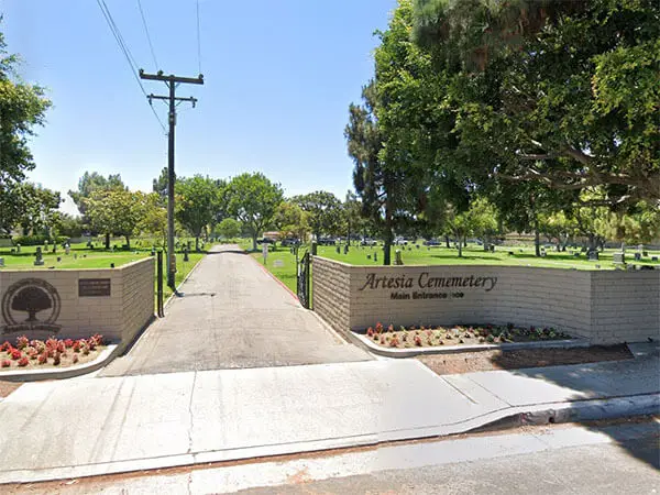 Main entrance of Artesia Cemetery District in Cerritos, CA, surrounded by green landscape and memorial headstones.