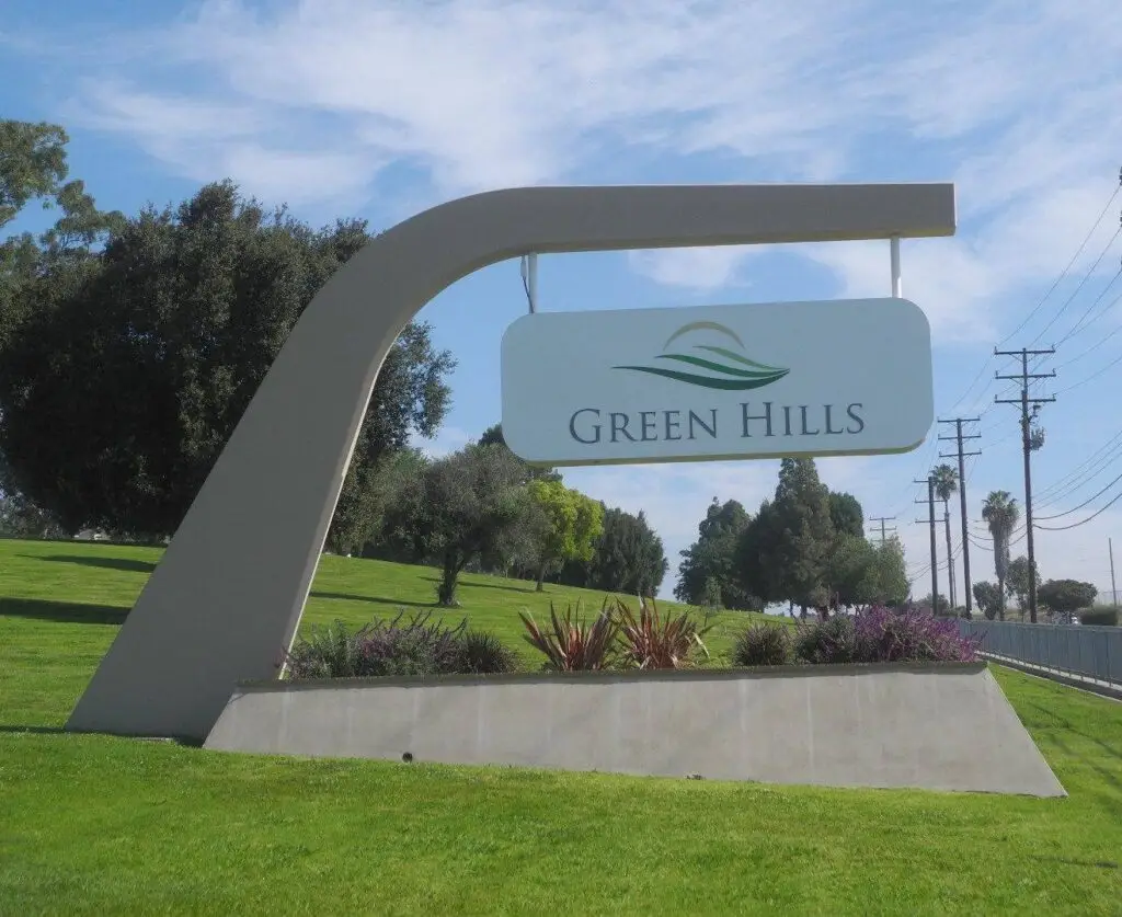 Entrance sign at Green Hills Memorial Park in Rancho Palos Verdes, CA, surrounded by green landscape.