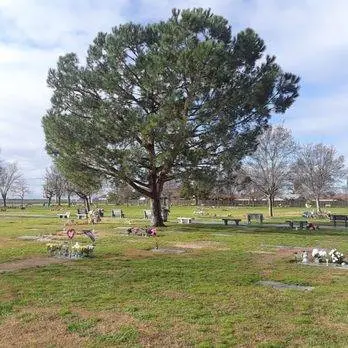 A peaceful green lawn and memorial area at North Kern Cemetery District, featuring flat grave markers and floral tributes.