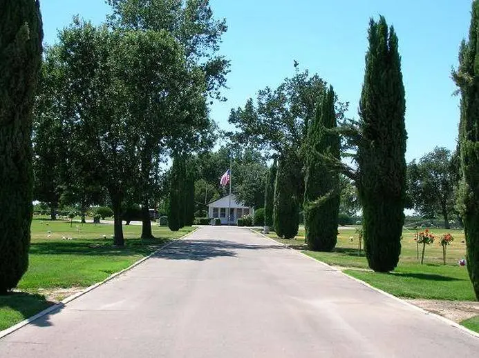 Entrance view of Oak Grove Cemetery in Laton, CA, featuring a tree-lined driveway and well-maintained memorial grounds