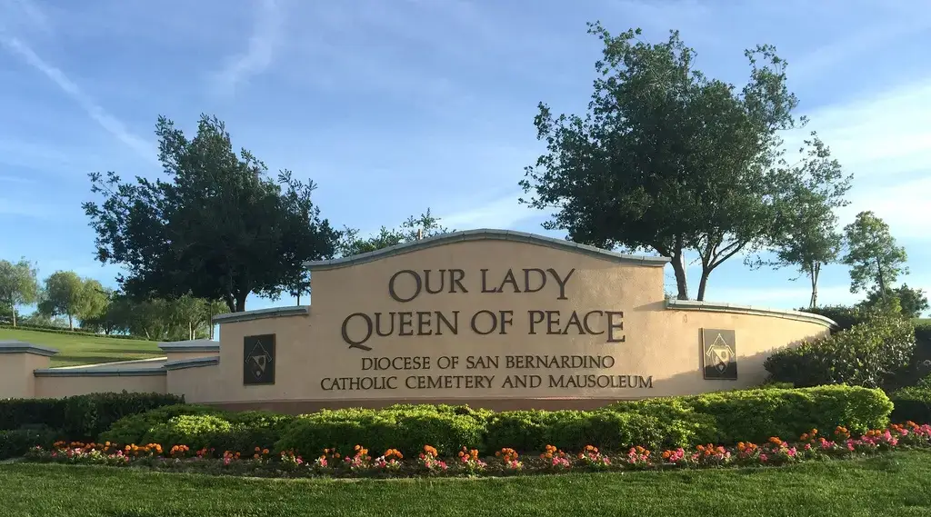 Entrance of Our Lady Queen of Peace Catholic Cemetery in San Bernardino, California, featuring a beautifully landscaped memorial space.