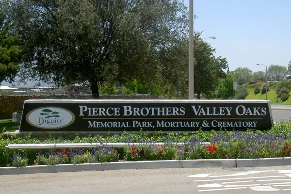 Entrance sign of Pierce Brothers Valley Oaks Memorial Park, Mortuary & Crematory in Westlake Village, CA, surrounded by lush landscaping and greenery.
