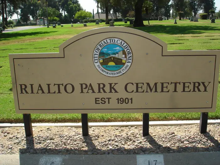 Entrance sign of Rialto Park Cemetery, established in 1901, surrounded by a green memorial park.