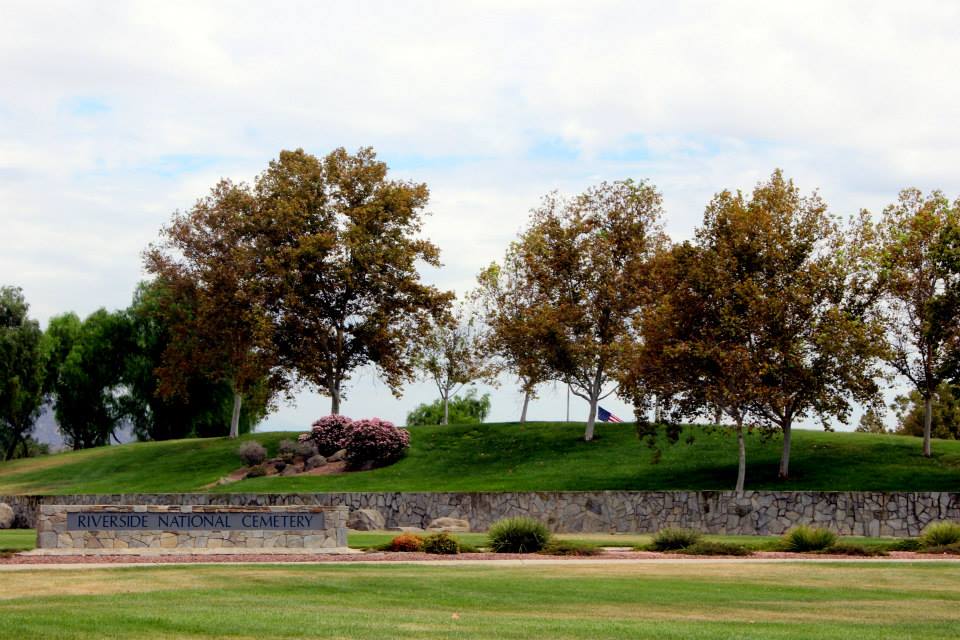 Entrance sign of Riverside National Cemetery surrounded by lush greenery and a peaceful landscape.