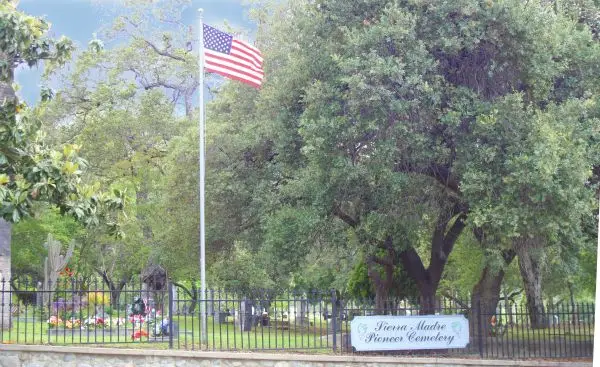 Entrance of Sierra Madre Pioneer Cemetery with an American flag and lush green surroundings, symbolizing a peaceful and historic final resting place.