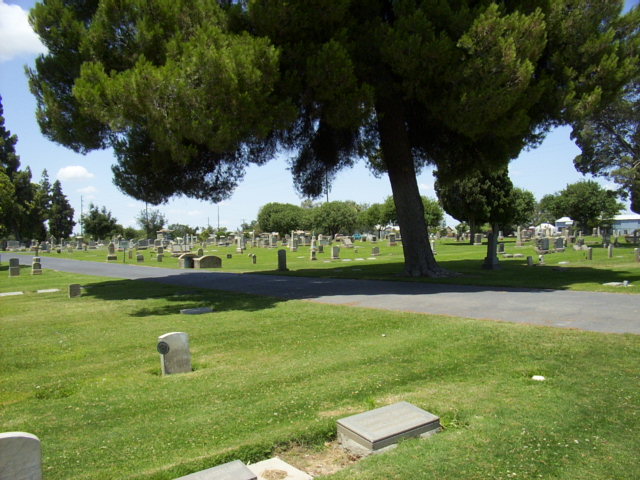 Scenic view of Hanford Cemetery, California, featuring well-maintained grounds and memorial headstones under lush trees