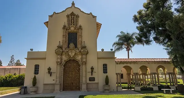 Historic Spanish-style chapel at Forest Lawn Long Beach, surrounded by palm trees and peaceful memorial gardens.
