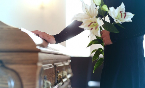 Woman holding lilies beside a casket at Rubidoux Mortuary